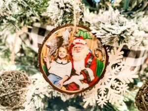 DIY wood slice photo ornament featuring a child with Santa on a Christmas tree.