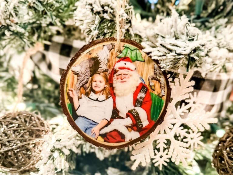DIY wood slice photo ornament featuring a child with Santa on a Christmas tree.