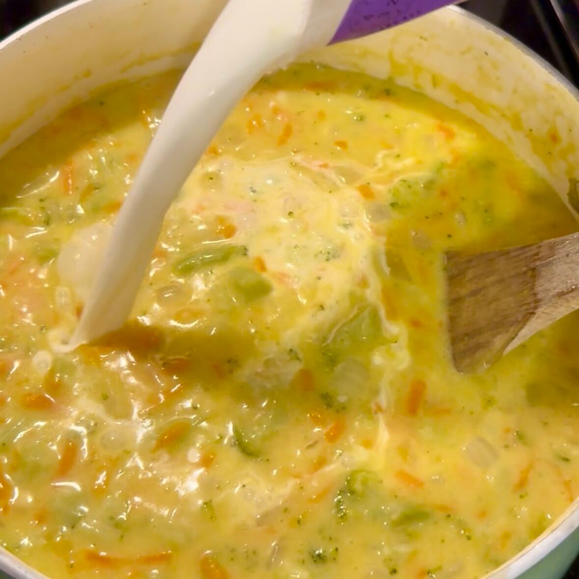 Pouring half and half into a pot of broccoli cheddar soup to make it extra creamy and rich.